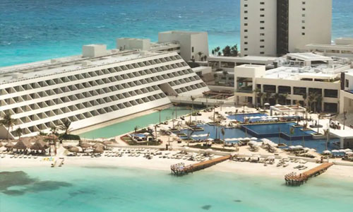 Picture of a beautiful beach resort in Cancun, Mexico.  The picture shows a marina, a harbor and  blue water.