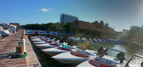 Picture of boats moored in a marina in Cancun, Mexico.  The picture shows several small boats at the pier on a bright and sunny day..