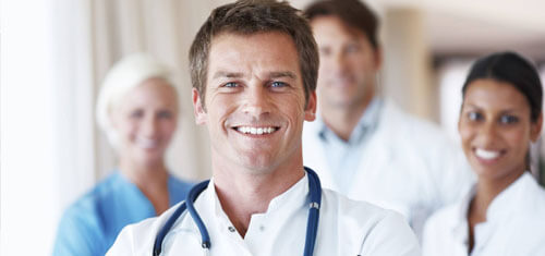 Picture of a group of doctors representing the quality care you will receive with the Top Plastic Surgeons in Cabo San Lucas, Mexico The picture shows a doctor in a white shirt with a stethoscope around his neck, and 3 associates standing behind him.