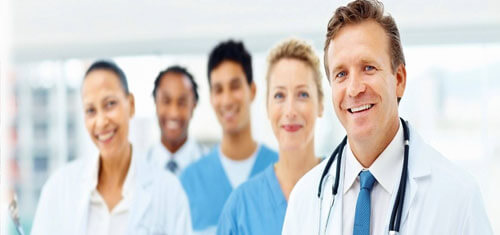 Picture of a doctor representing the top plastic surgeons in Cancun, Mexico.  The picture shows a doctor in a white coat standing with 4 members of his staff.