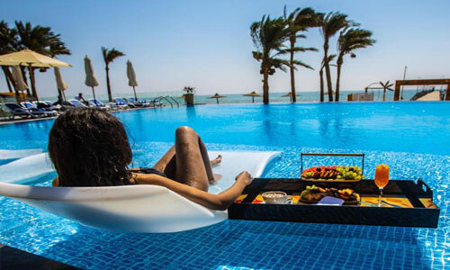 Picture of beautiful beach in Cancun, Mexico.  The picture shows a girl looking into the ocean from the pool.