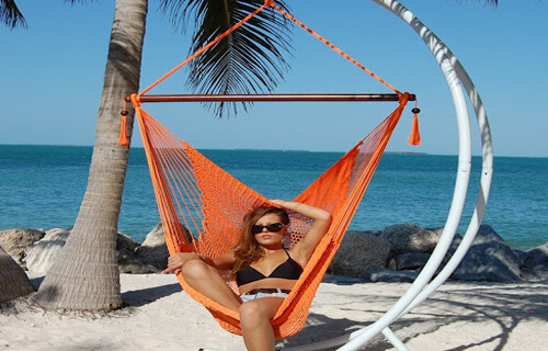 Picture of a woman in a two-piece bikini lying in a hammock on the beach in Cancun, Mexico.
