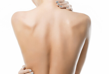 Picture of a woman with her back to the camera and happy with her perfect back liposuction procedure she had with top plastic surgeons in beautiful Cancun, Mexico.  She has two hands positioned to highlight the areas of her back liposuction.