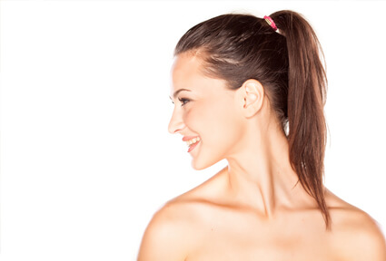 Picture of a woman with long brown hair, slightly turned to the side of the camera and happy with her perfect ear surgery procedure she had with top plastic surgeons in beautiful Cancun, Mexico.  The angle of the camera clearly shows one ear.