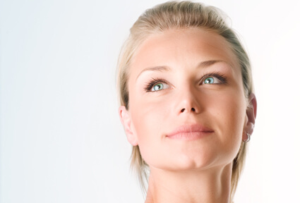 Picture of a woman with blonde hair, facing the camera, and happy with her perfect face lift procedure she had at Top Plastic Surgeons with top plastic surgeons in beautiful Cancun, Mexico.  The woman is looking slightly upwards to show her satisfaction with her face lift.