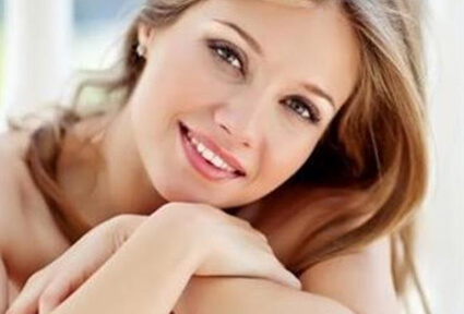 Picture of a trim woman sitting with arms crossed, and happy with her perfect Labiaplasty she had with top plastic surgeons in beautiful Cancun, Mexico.  The woman has long sandy blonde hair and is facing the camera with head slightly tilted.