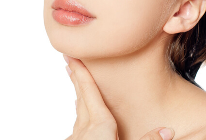 Picture of a woman with short brown hair, turned slightly away from the camera, and happy with her perfect neck lift procedure she had with top plastic surgeons in beautiful Cancun, Mexico.  The woman has her hand on her neck showing the results.