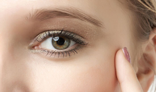 Picture of a woman, facing the camera and happy with her perfect eyelid lift procedure she with Cancun MedVentures in beautiful Cancun, Mexico.  The woman has her hand to the side of her face and is pointing to the side of her eye with her index finger.