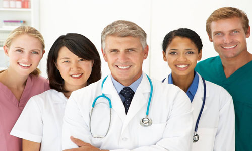 Picture of a smiling medical team representing doctors in beautiful Cancun, Mexico.  The picture shows five members of the medical group standing together, facing the camera, and smiling.